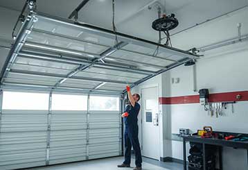 Professional garage door technician servicing an overhead garage door in a well-equipped Anaheim garage