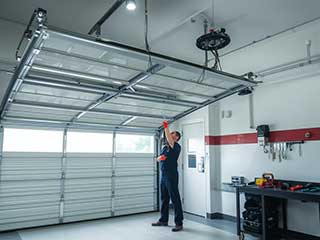 Professional garage door technician servicing an overhead garage door in a well-equipped Anaheim garage