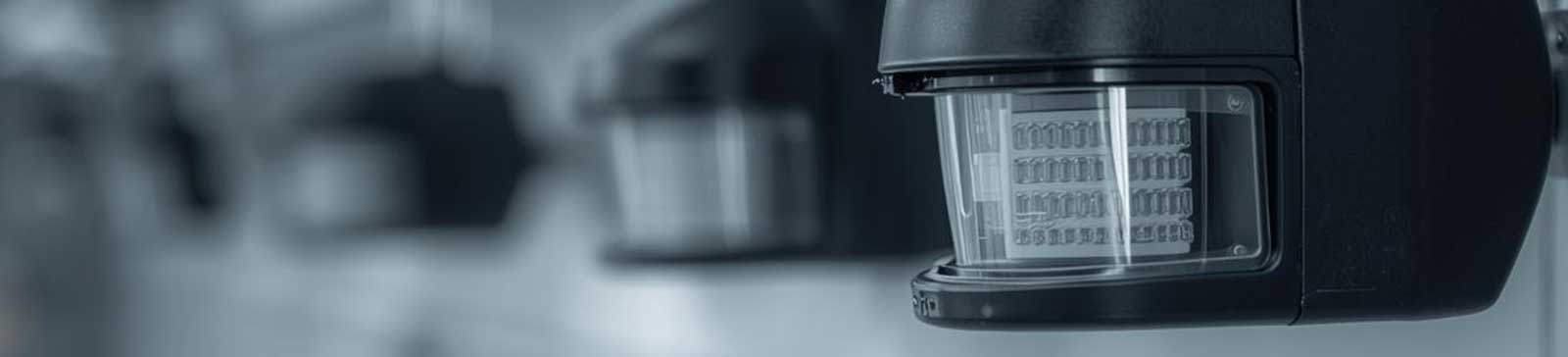 Close-up of a motion-detecting safety sensor mounted on a garage door track in an Anaheim home