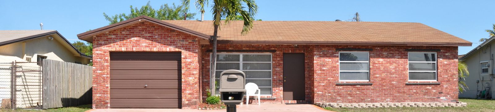 Front view of single-story Anaheim brick house with brown paneled garage door, palm tree, and sunny yard—representing local garage door service