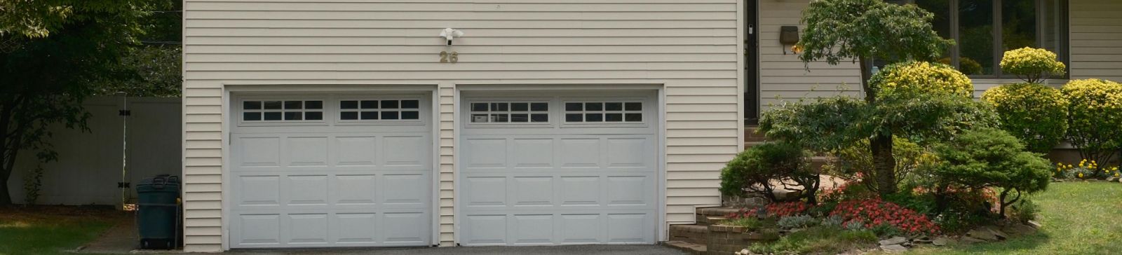Suburban home with two newly installed white sectional garage doors and manicured landscaping by Garage Door Repair Anaheim