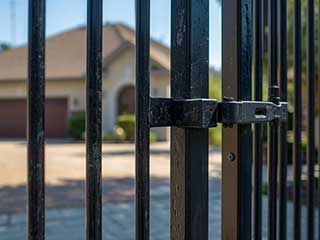 Sturdy black metal gate and latch in front of Anaheim home, highlighting professional gate repair and installation services