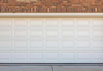 Closed white-paneled overhead garage door installed in a brick Anaheim home, symbolizing professional repair and service
