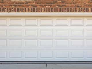 Closed white-paneled overhead garage door installed in a brick Anaheim home, symbolizing professional repair and service