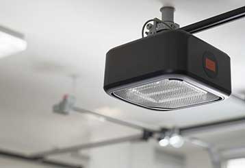 Close-up of modern garage door opener installed on ceiling rail, highlighting automated technology and maintenance needs